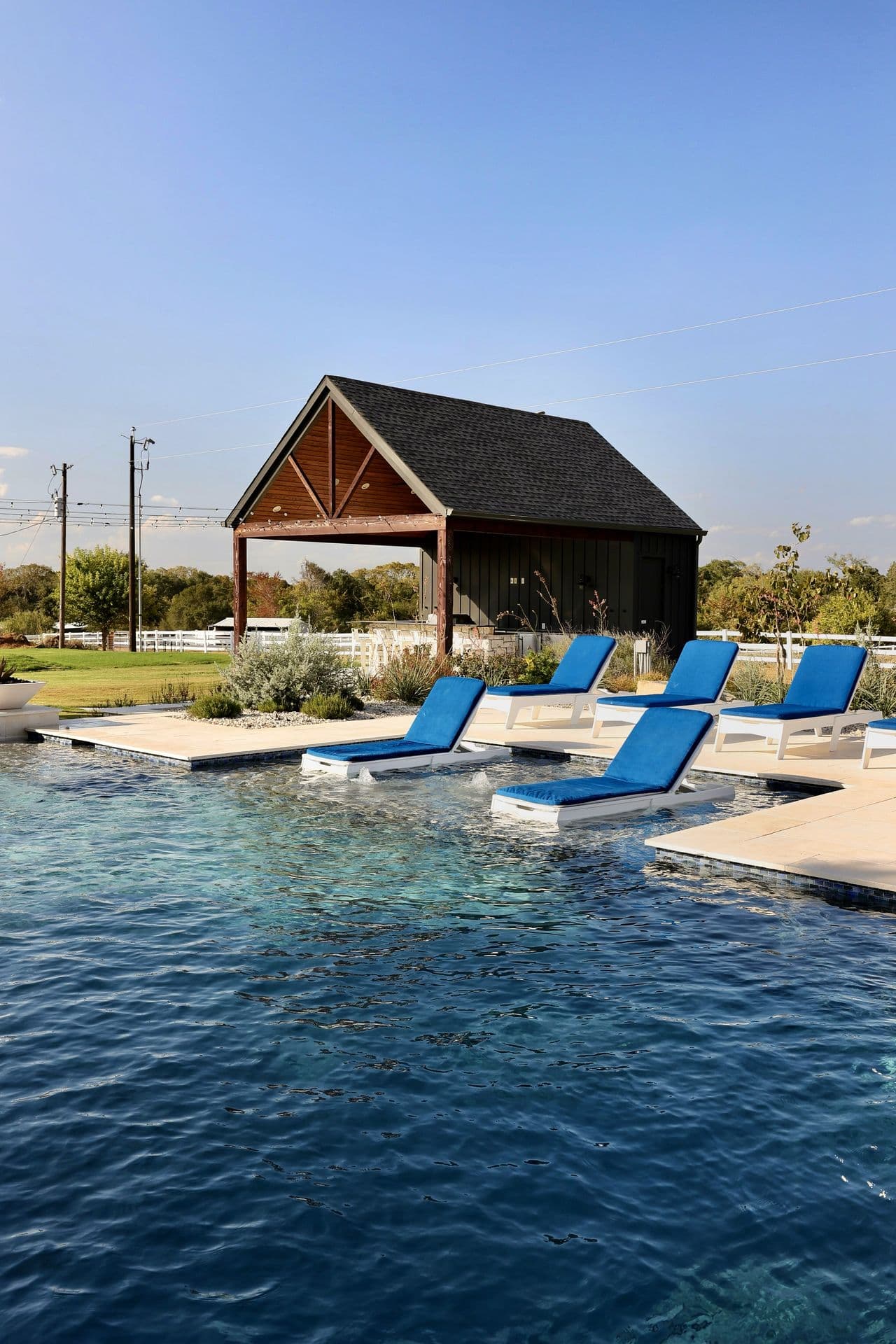 The pool with loungers set on in-water ledges beside the pavilion